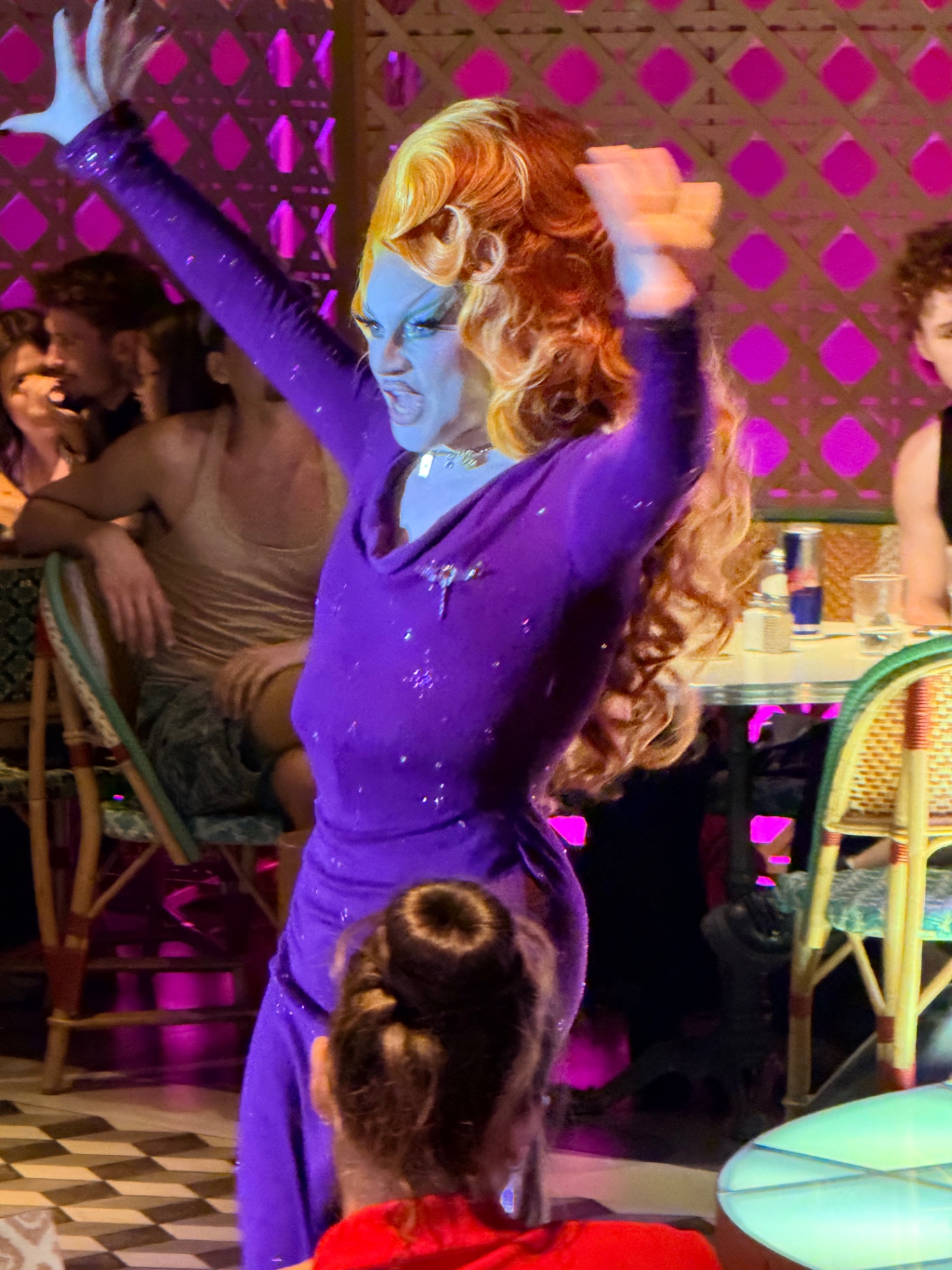 Performance drag en robe violette devant le public attablé